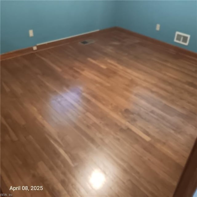 unfurnished room with visible vents, baseboards, and wood finished floors