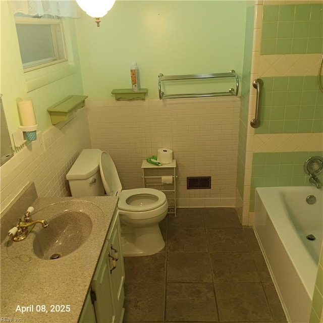full bathroom with vanity, tile patterned flooring, toilet, wainscoting, and tile walls