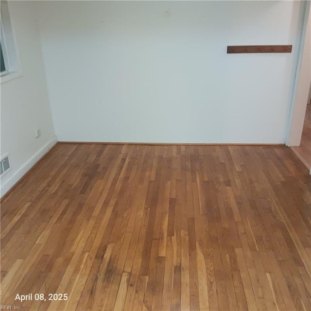 unfurnished room featuring visible vents, baseboards, and hardwood / wood-style flooring