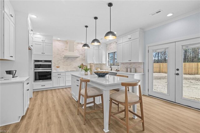 3545 Winston Ave, Virginia Beach, VA 23456 - kitchen featuring custom exhaust hood, visible vents, tasteful backsplash, white cabinetry, and french doors