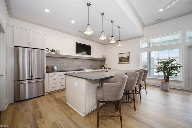 kitchen featuring dark countertops, a sink, freestanding refrigerator, tasteful backsplash, and ornamental molding