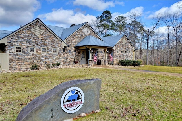 craftsman-style home featuring metal roof, stone siding, and a front lawn