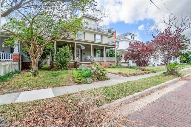 traditional style home with a front yard, a porch, and fence