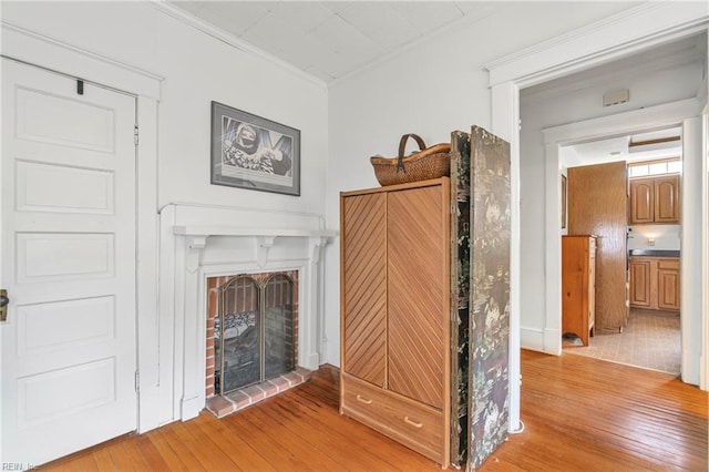 unfurnished living room with a fireplace, light wood-type flooring, and ornamental molding