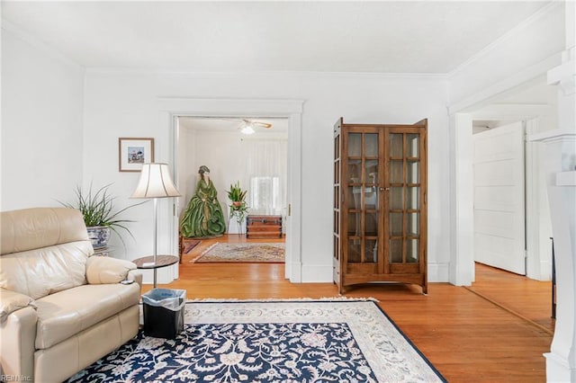 sitting room featuring crown molding, wood finished floors, and a ceiling fan