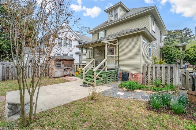 traditional style home with an outbuilding, a fenced backyard, a patio, and a storage unit