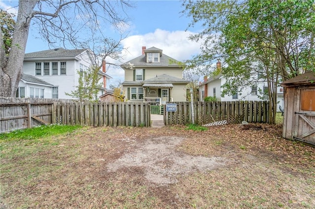 rear view of house with a chimney and a fenced front yard