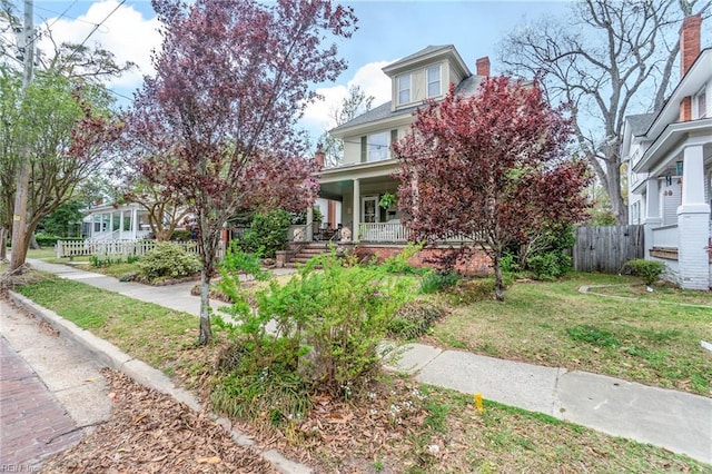 view of front of home featuring a porch, fence, and a front lawn