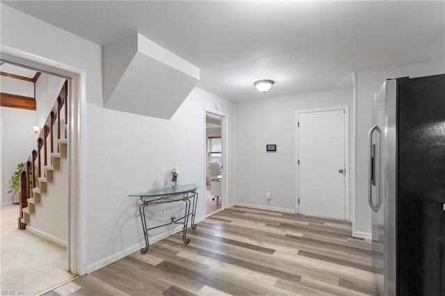 interior space with light wood-style floors, baseboards, and stairway