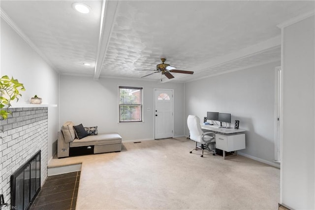 office with crown molding, a ceiling fan, carpet floors, a brick fireplace, and baseboards