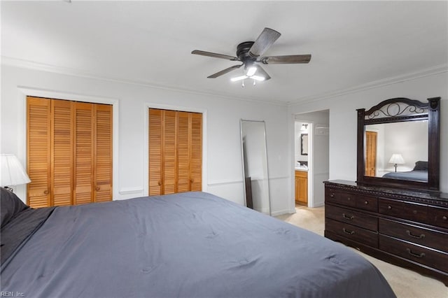 bedroom with light carpet, a ceiling fan, two closets, and ornamental molding