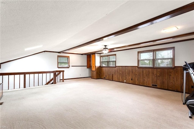 interior space with light colored carpet, ceiling fan, wainscoting, and a textured ceiling