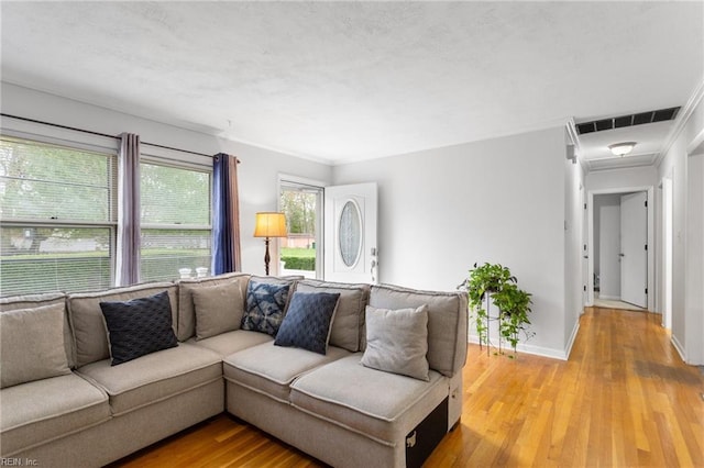 living room with light wood-style floors, baseboards, visible vents, and a textured ceiling