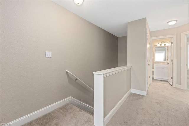 hallway featuring carpet floors, baseboards, and an upstairs landing