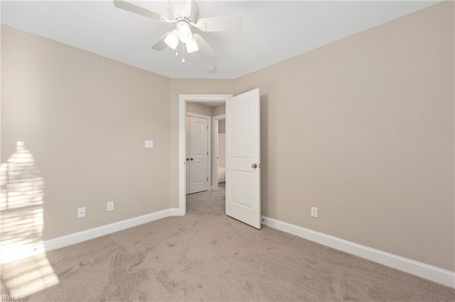 spare room with light carpet, baseboards, and a ceiling fan