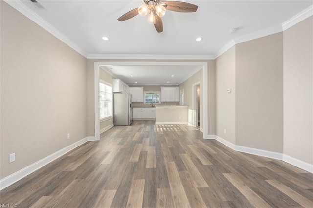 unfurnished living room featuring ornamental molding, baseboards, a ceiling fan, and wood finished floors