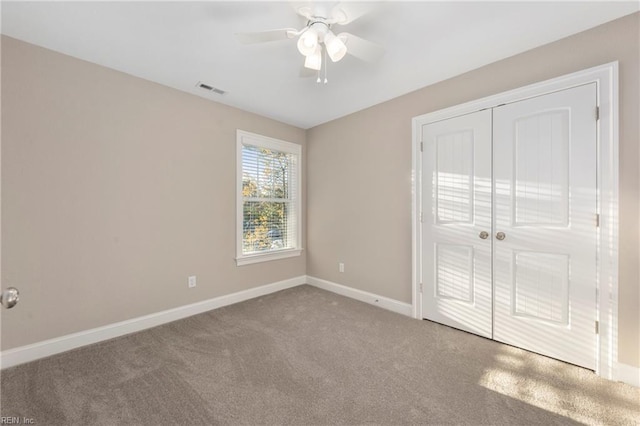 unfurnished bedroom featuring ceiling fan, carpet, a closet, visible vents, and baseboards