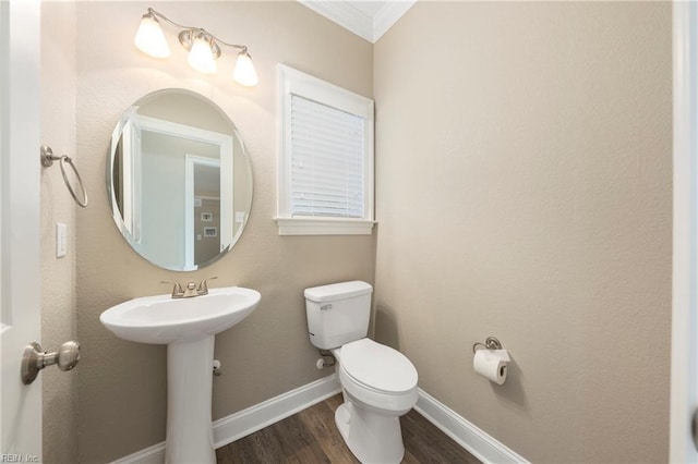 bathroom with baseboards, crown molding, toilet, a sink, and wood finished floors