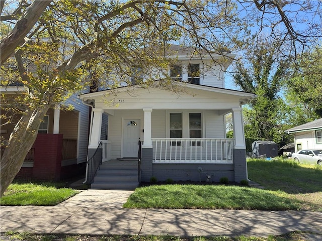 traditional style home featuring covered porch and a front lawn