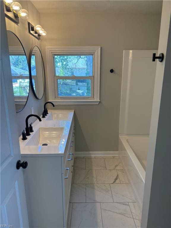 bathroom with vanity, marble finish floor, baseboards, and plenty of natural light