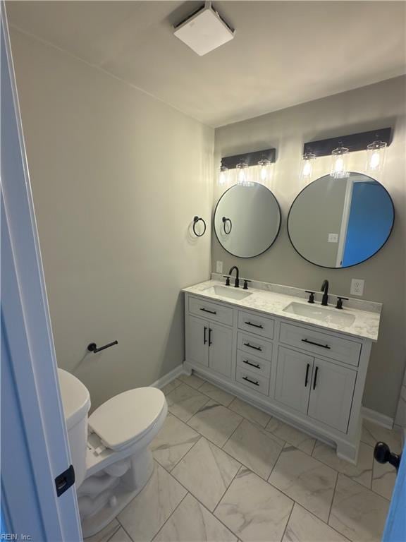 bathroom featuring double vanity, marble finish floor, a sink, and toilet
