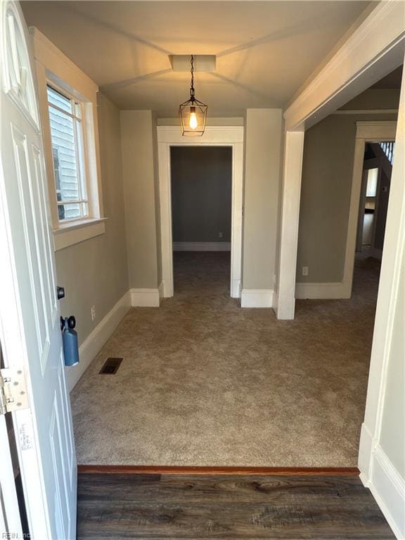 interior space with baseboards, dark colored carpet, and visible vents