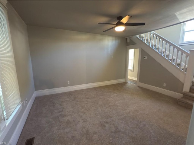 unfurnished living room featuring visible vents, a ceiling fan, carpet floors, and stairs