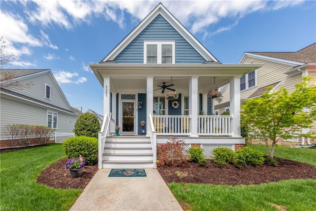 view of front facade with ceiling fan, covered porch, and a front yard