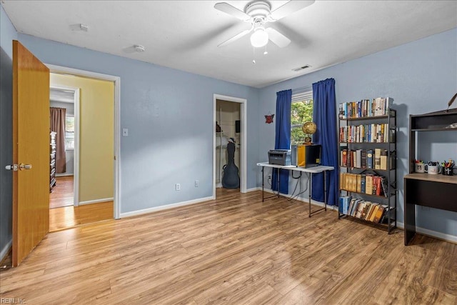 interior space featuring wood finished floors, ceiling fan, baseboards, and visible vents