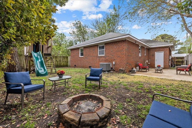back of house featuring a fire pit, a fenced backyard, a playground, a patio, and brick siding