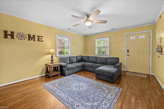 living room featuring a ceiling fan, wood finished floors, ornamental molding, and plenty of natural light