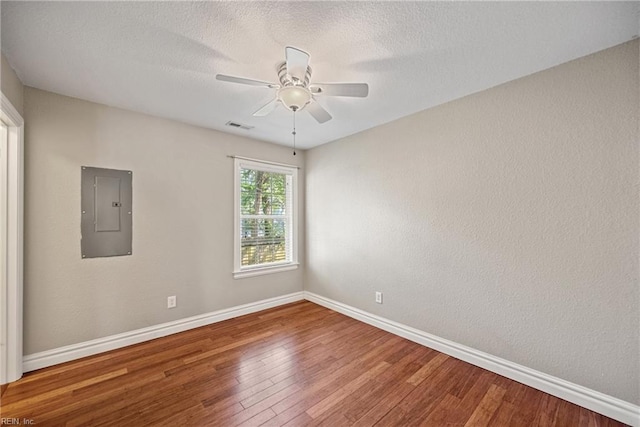 unfurnished room featuring visible vents, baseboards, electric panel, a ceiling fan, and hardwood / wood-style floors