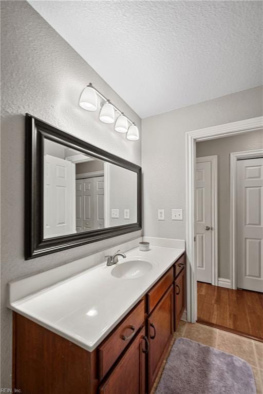 bathroom with tile patterned flooring, vanity, and a textured ceiling