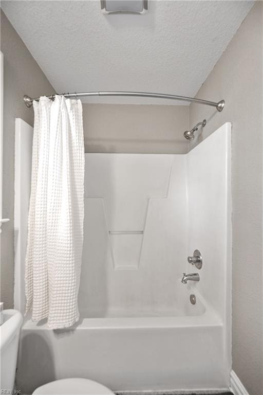full bath with toilet, shower / bath combo, and a textured ceiling
