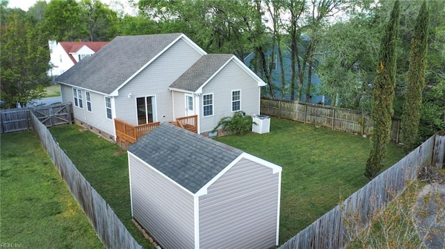 exterior space with a shingled roof, a yard, a fenced backyard, and a wooden deck