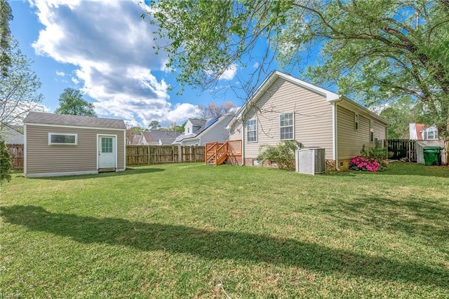 view of yard with a fenced backyard, central AC unit, and an outdoor structure