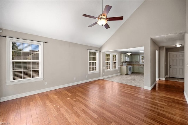 unfurnished living room with a wealth of natural light, light wood-type flooring, ceiling fan, and baseboards