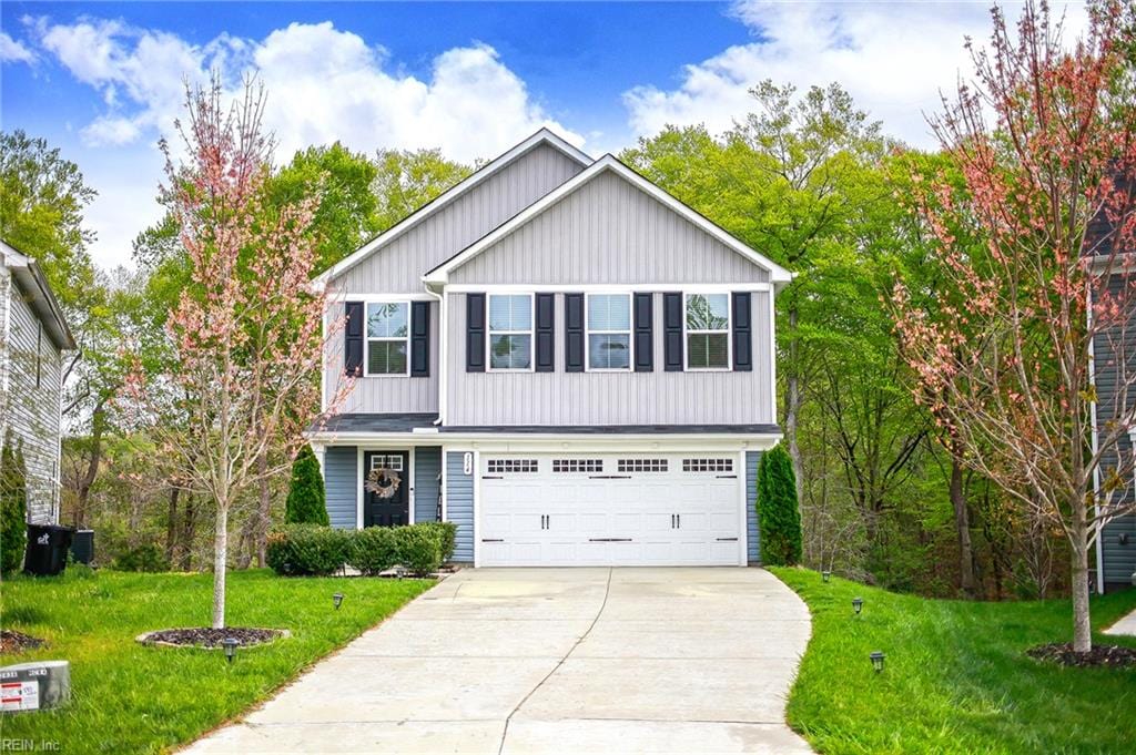 view of front of house with an attached garage, driveway, and a front lawn