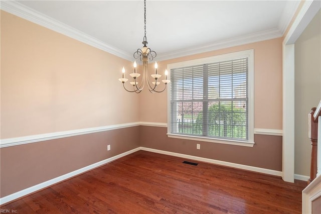 empty room with ornamental molding, visible vents, a chandelier, wood finished floors, and baseboards
