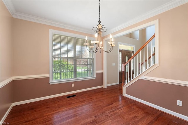unfurnished dining area featuring crown molding, an inviting chandelier, visible vents, wood finished floors, and baseboards