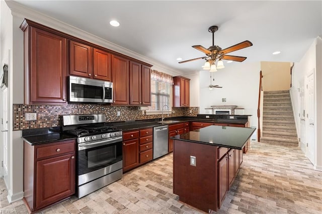 kitchen with appliances with stainless steel finishes, backsplash, a kitchen island, ceiling fan, and a sink