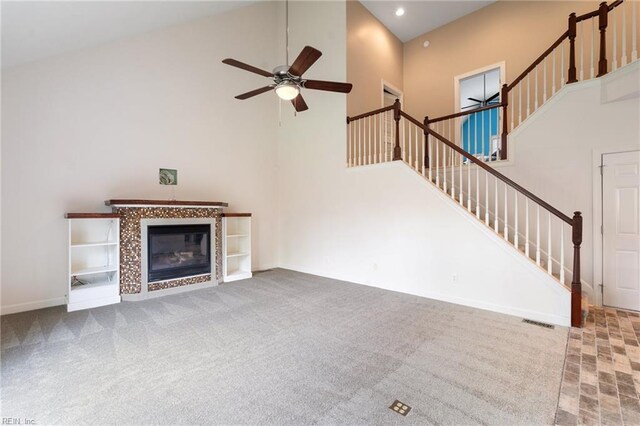 unfurnished living room with a tiled fireplace, a ceiling fan, recessed lighting, a towering ceiling, and stairs