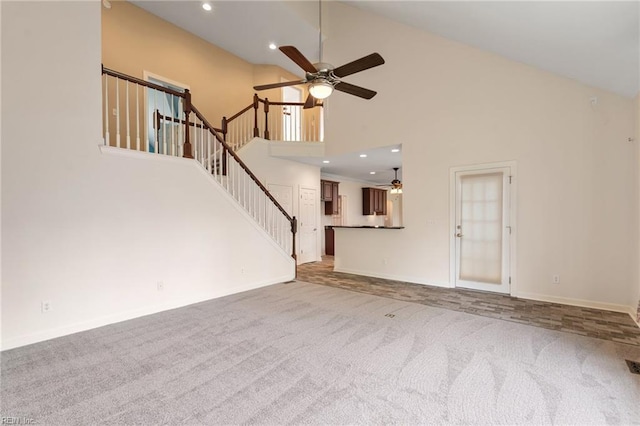 unfurnished living room with high vaulted ceiling, ceiling fan, recessed lighting, carpet flooring, and stairs
