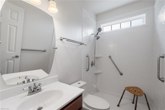 full bath with a tile shower, vanity, and toilet