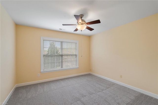 carpeted spare room featuring visible vents, baseboards, and a ceiling fan