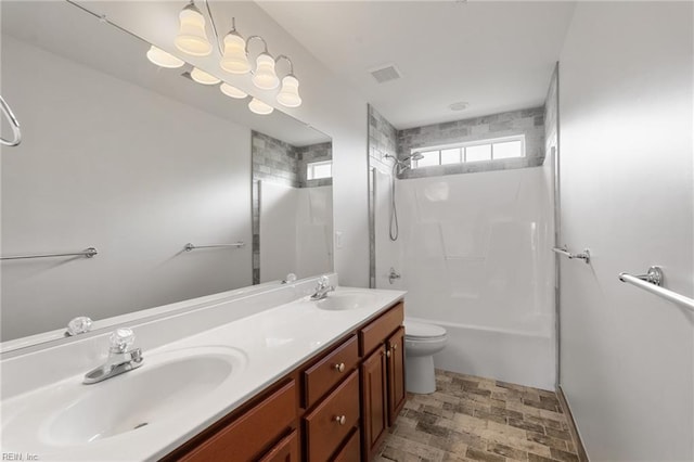 bathroom with double vanity, a sink, toilet, and shower / washtub combination