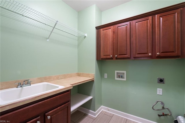 washroom featuring hookup for a washing machine, electric dryer hookup, a sink, baseboards, and cabinet space