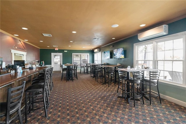 carpeted dining space with ornamental molding, visible vents, a wealth of natural light, and an AC wall unit