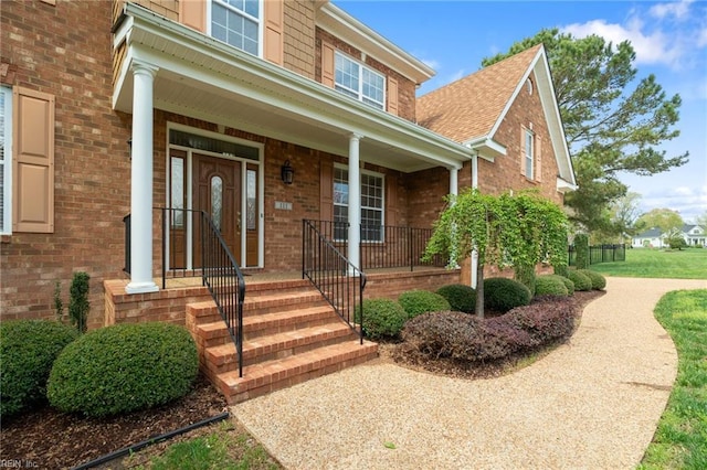 entrance to property featuring a porch and brick siding