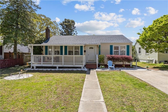 view of front of house featuring a porch, a chimney, fence, and a front lawn